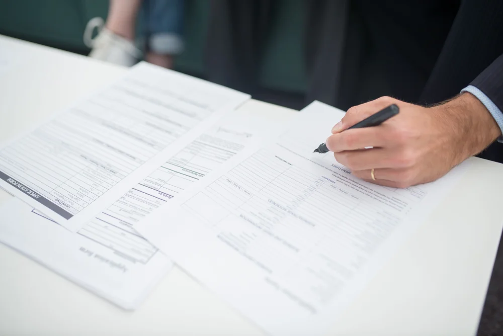 A hand holding a pen over documents on a desk